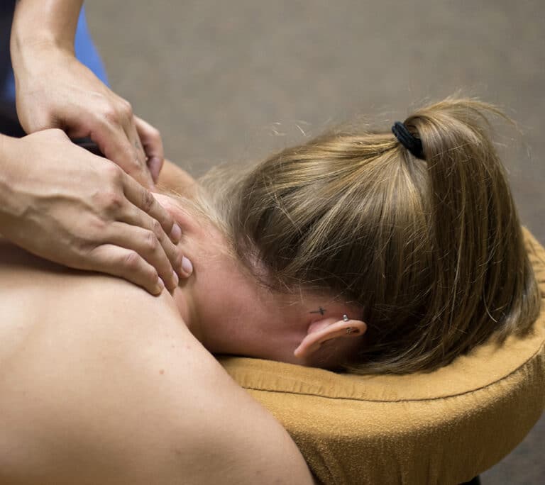 En fysioterapeut håndterer nakke- og skulderproblemer hos en patient.